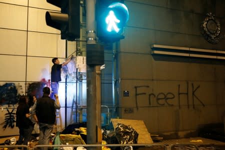 Plainclothes police officer removes a poster displayed on a wall outside police headquarters after a rally ahead of the G20 summit in Hong Kong