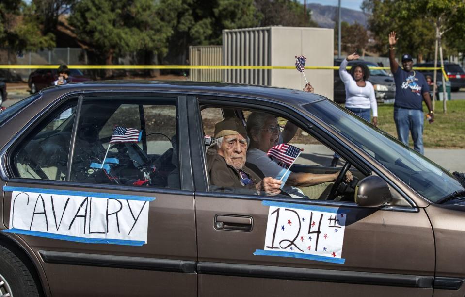 A man looks out the passenger window of a car with banners that read "Cavalry 124th"