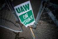 FILE - In this Monday, Sept. 16, 2019, file photo, a United Auto Workers strike sign rests between the chains of a locked gate entrance outside of Flint Engine Operations in Flint, Mich. As the United Auto Workers’ strike against General Motors continues, consumers, the company and striking workers are starting to get pinched. (Jake May/The Flint Journal via AP, File)