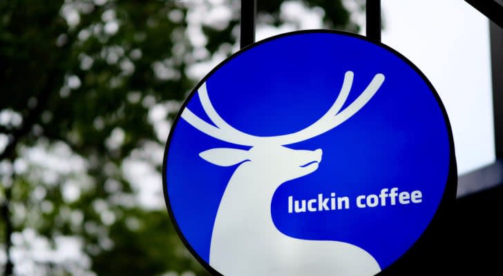 close up luckin coffee's (LKNCY) logo on light box hangging outside of coffee booth. Blur green trees background.