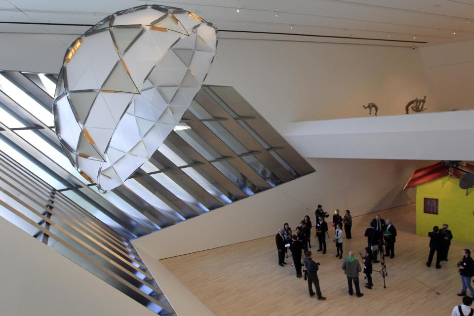 In this Nov. 9, 2012 photo members of the media tour the Eli and Edythe Broad Art Museum on Michigan State University's campus in East Lansing, Mich. The canopy sculpture seen at upper left is "Red Factor" by Inigo Manglano-Ovalie. (AP Photo/Carlos Osorio)