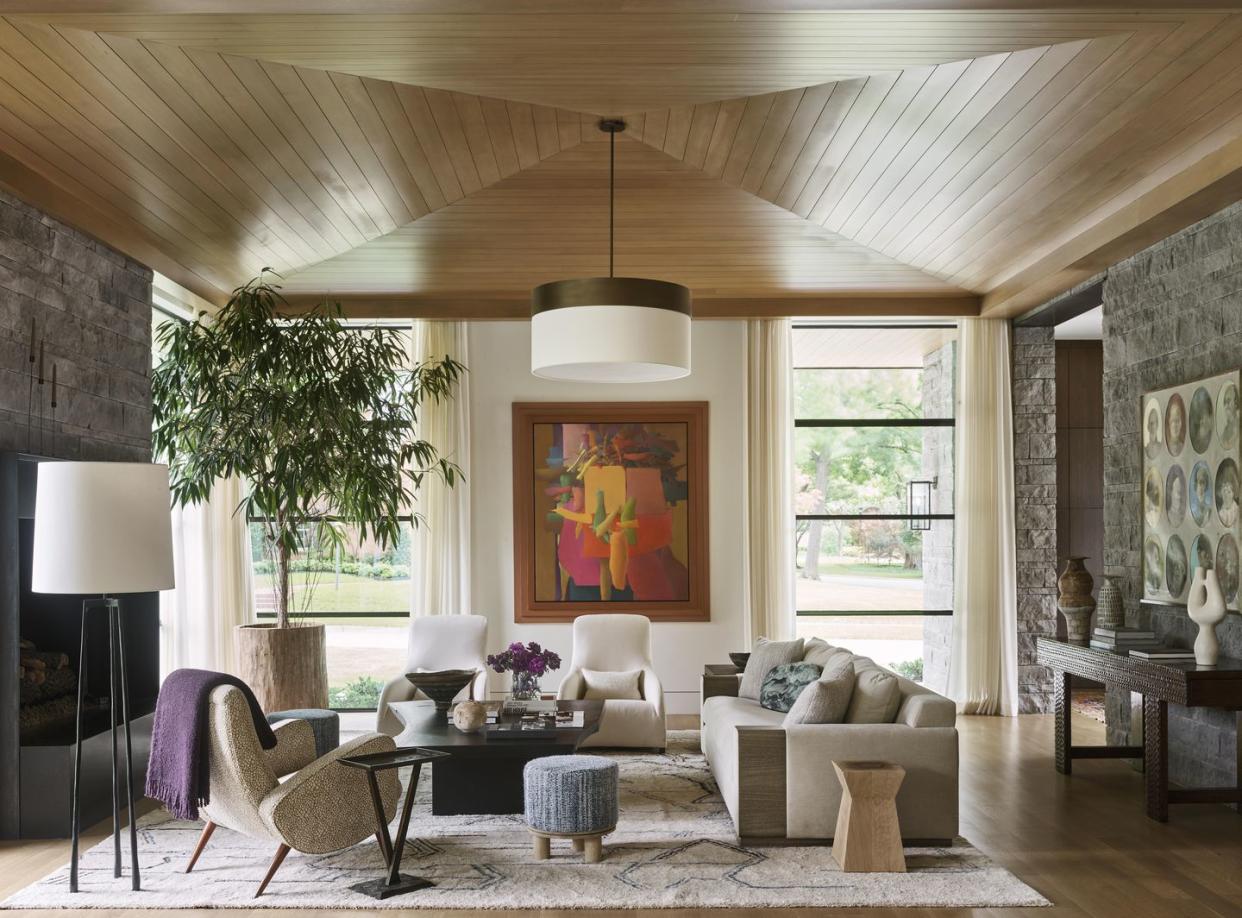 a sofa and chairs in a large living room with a paneled wood ceiling