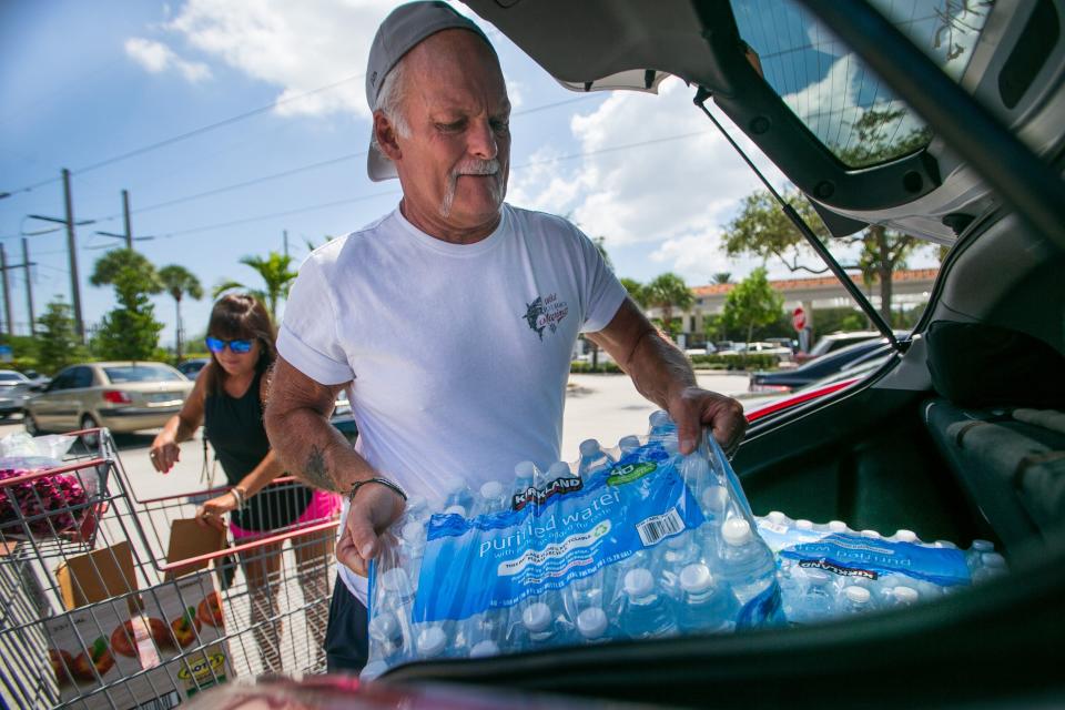 Tony and Shelly Kay, both of Delray Beach, load cases of water and other supplies into the trunk of their car after shopping at Costco on Friday, September 23, 2022, in Boca Raton.