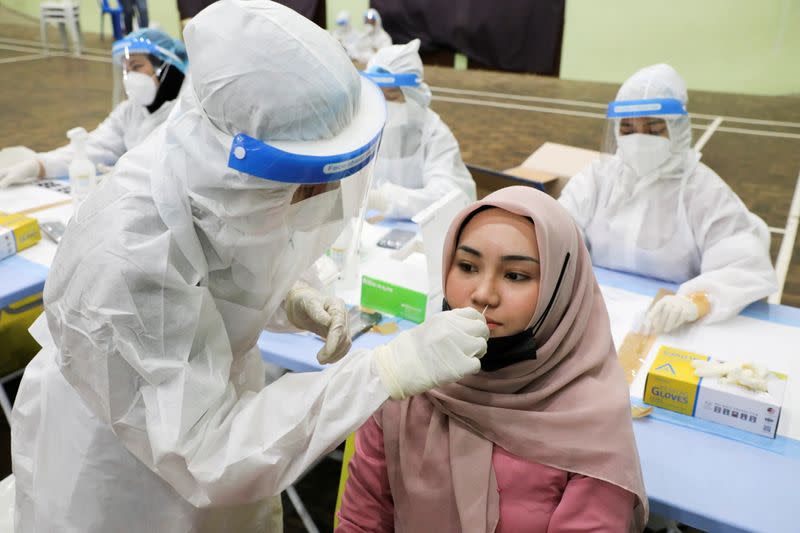 FILE PHOTO: A medical worker collects a swab sample from a woman to be tested for COVID-19 in Kuala Lumpur