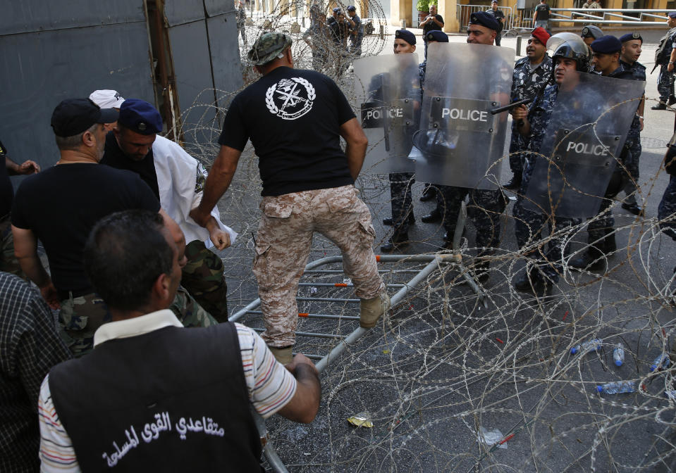 Lebanese retired soldiers, left, step on the barbed wires, as they try to enter the parliament building where lawmakers and ministers are discussing the draft 2019 state budget, in Beirut, Lebanon, Friday, July 19, 2019. The budget is aimed at averting a financial crisis in heavily indebted Lebanon. But it was met with criticism for failing to address structural problems. Instead, the budget mostly cuts public spending and raises taxes. (AP Photo/Hussein Malla)