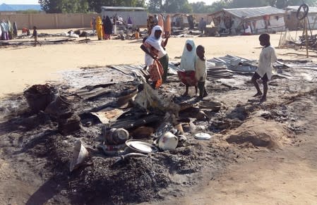 FILE PHOTO: People stand amid the damage at a camp for displaced people after an attack by suspected members of the Islamist Boko Haram insurgency in Dalori