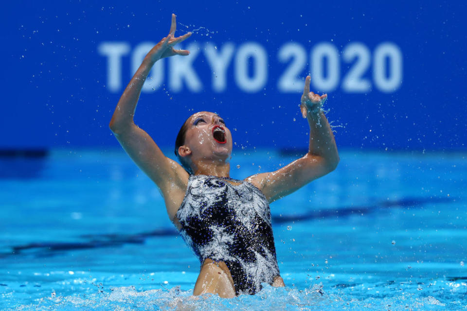 A swimmer leaning back, arms raised, mouth wide open