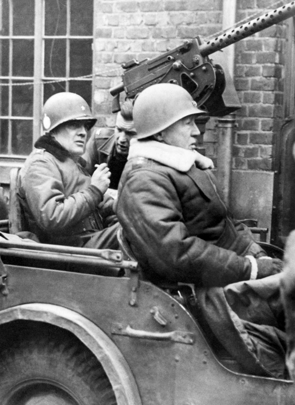 FILE - In this Jan. 15, 1945 file photo, U.S. Brig. Gen. Anthony C. McAuliffe, left, and Lt. Gen. George S. Patton, Jr., right, are seated in Jeep after made an inspection tour of the 101st Airborne division. At first, German forces drove so deep through the front line in Belgium and Luxembourg that the month-long fighting came to be known as The Battle of the Bulge. When the Germans asked one American commander to surrender, the famous reply came: “Nuts!" By Christmas, American troops had turned the tables on the Germans. Veterans are heading and on Monday, Dec. 16, 2019 when they will mix with royalty and dignitaries to mark perhaps the greatest battle in U.S. military history. (AP Photo, File)