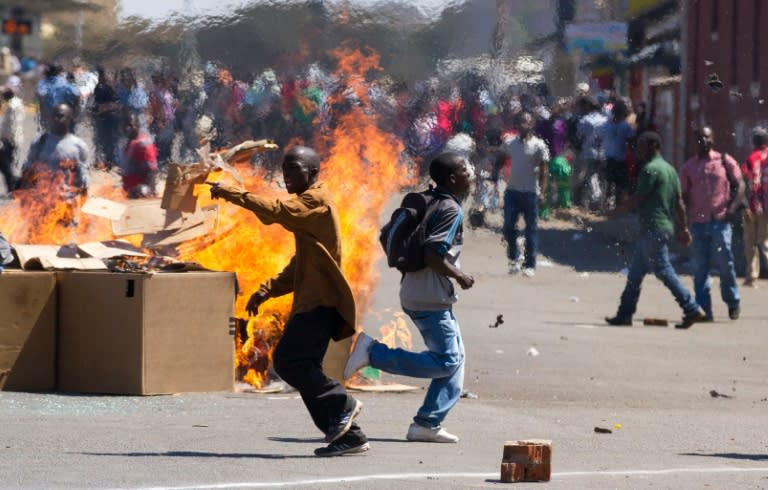 Demonstrators in Harare began throwing stones at police while some set tyres ablaze and others pulled down the sign for a street named after Mugabe