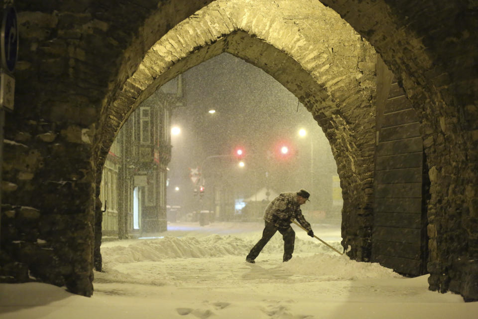 A resident shovels snow under an archway in Wernigerode, Germany, early Sunday morning, Feb. 7, 2021. Low Tristan has caused huge amounts of snow in the Harz mountains, like here in Wernigerode. (Matthias Bein/dpa via AP)