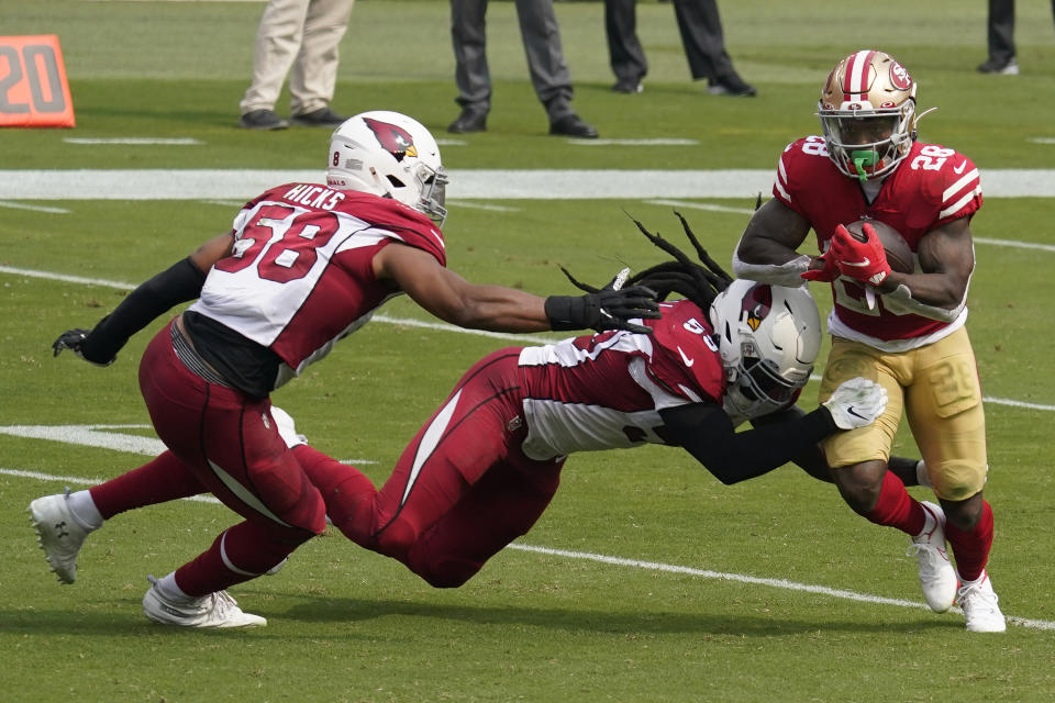 San Francisco 49ers running back Jerick McKinnon (28) runs against Arizona Cardinals middle linebacker Jordan Hicks (58) and outside linebacker De'Vondre Campbell during the first half of an NFL football game in Santa Clara, Calif., Sunday, Sept. 13, 2020. (AP Photo/Tony Avelar)