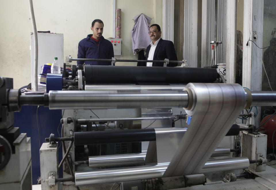 In this Monday, March 3, 2014 photo, Adel Abd ElSadk, left, owner of the pharmaceutical packaging company Trustpack, talks with an employee manning one of the machines at his factory which has been financed in part by loans from the Social Development Fund, located just outside Cairo, Egypt. The program, called “The Project” in Arabic, highlights entrepreneurship and small business acumen - something experts say is more crucial than ever as Egypt tries to claw its way out of tough economic times. (AP Photo/Amr Nabil)