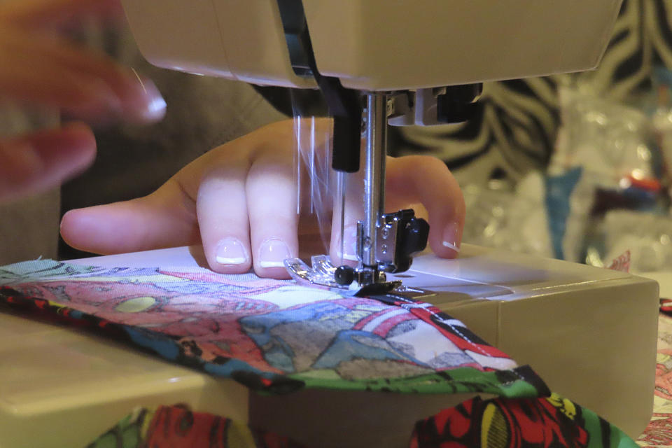 Audrina Demma sews a pediatric hospital gown in the basement of her Freehold, N.J., home on June 19, 2024. She and her sister Giuliana have sewn and donated 1,800 hospital gowns to sick children in 36 states plus Africa. Giuliana was inspired by seeing her baby cousin wearing an ugly, ill-fitting gown while hospitalized with brain cancer in 2017. (AP Photo/Wayne Parry)