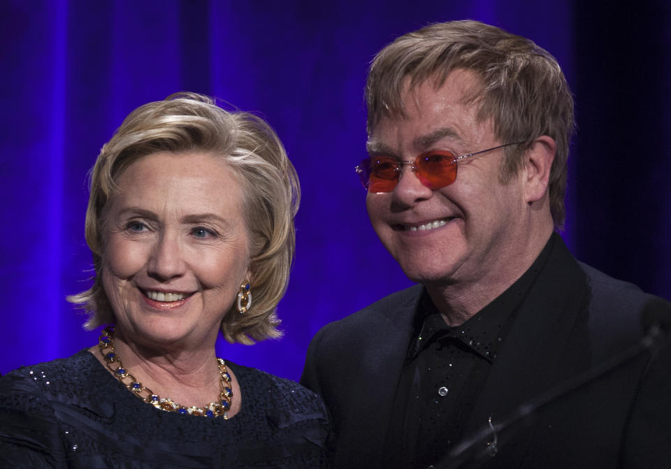 Former Secretary of State Hillary Clinton, left, poses onstage for a photograph with Elton John after receiving her Founders award during the Elton John AIDS Foundation's 12th Annual "An Enduring Vision" benefit gala at Cipriani Wall Street on Tuesday, Oct. 15, 2013, in New York.