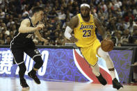 Los Angeles Lakers' Lebron James, right, drives against Brooklyn Nets' Rodions Kurucs, left, during their preseason NBA game in Shanghai, China, Thursday, Oct. 10, 2019. In response to the NBA defending Daryl Morey's freedom of speech, Chinese officials took it away from the Los Angeles Lakers and Brooklyn Nets, with the usual media sessions canceled in Shanghai, including a scheduled news conference from NBA Commissioner Adam Silver and postgame news conferences with the teams. (AP Photo) /// DQo=