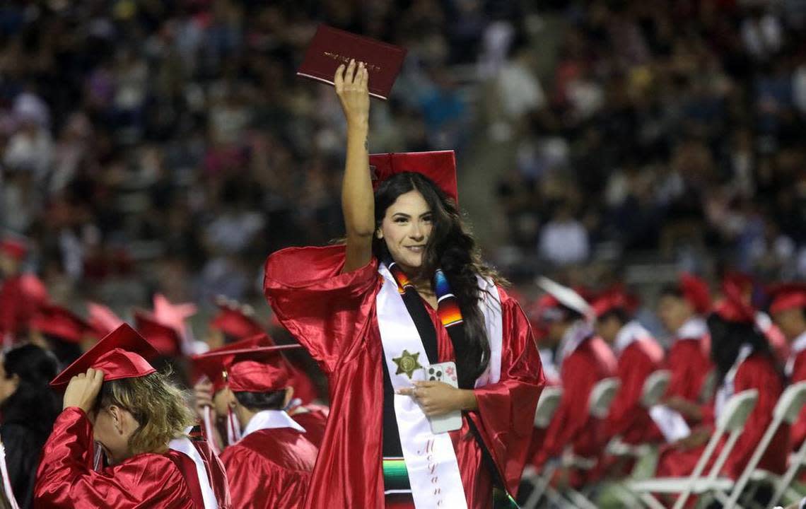 A graduate holds up her diploma during the McLane High graduation at the school stadium on June 6, 2023.