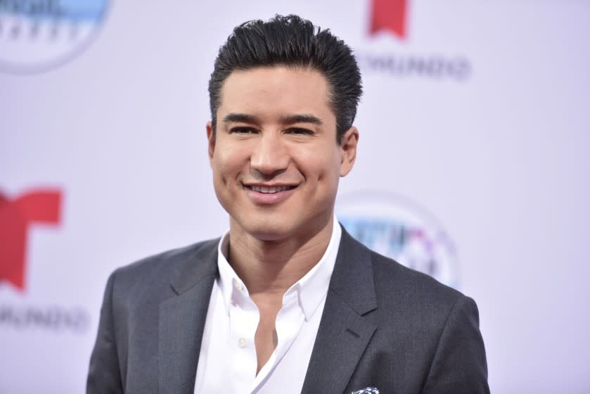 Mario Lopez smiling in a dark grey suit