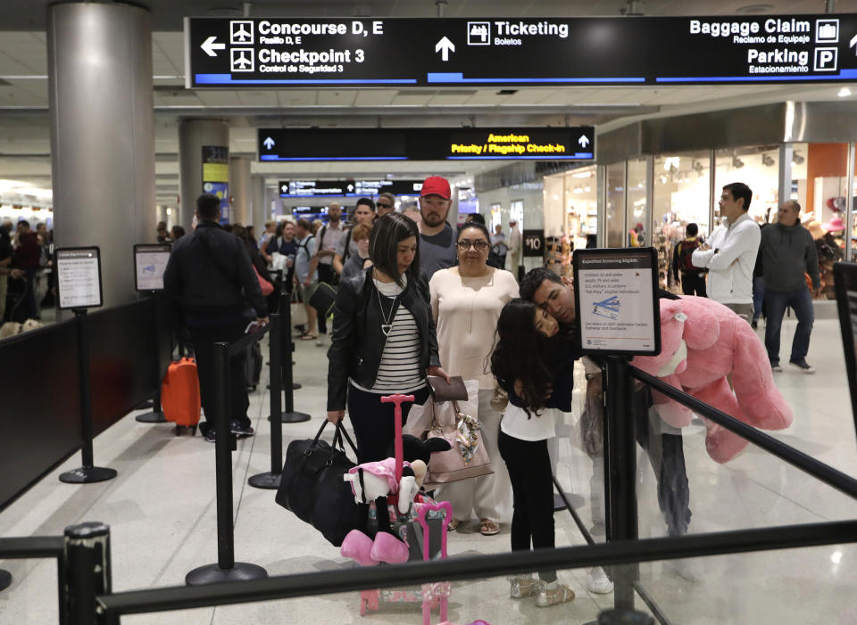 FILE- In this Jan. 18, 2019, file photo Carlos Gonzalez, right, hugs his daughter as she waits in line at a security checkpoint at Miami International Airport in Miami. The strain of a 34-day partial government shutdown is weighing on the nation's air-travel system, both the federal workers who make it go and the airlines that depend on them. Unions that represent air traffic controllers, flight attendants and pilots are growing concerned about safety with the shutdown well into its fifth week. (AP Photo/Lynne Sladky, File)