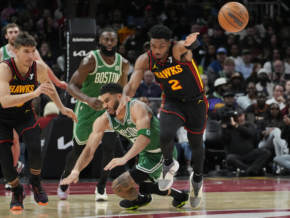 Atlanta Hawks guard Trent Forrest (2) and Boston Celtics forward Jayson Tatum (0) chase down a loose ball during the second half of an NBA basketball game Thursday, March 28, 2024, in Atlanta. (AP Photo/John Bazemore)