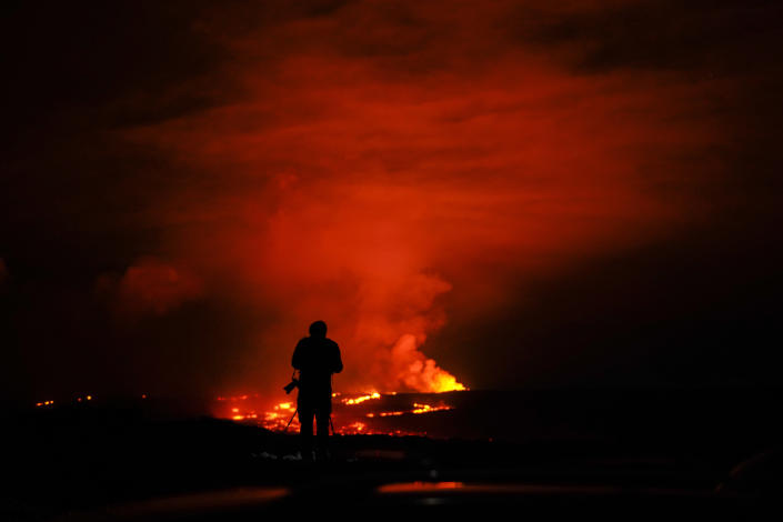 A photographer takes pictures of the Mauna Loa volcano as it erupts Wednesday, Nov. 30, 2022, near Hilo, Hawaii. (AP Photo/Gregory Bull)