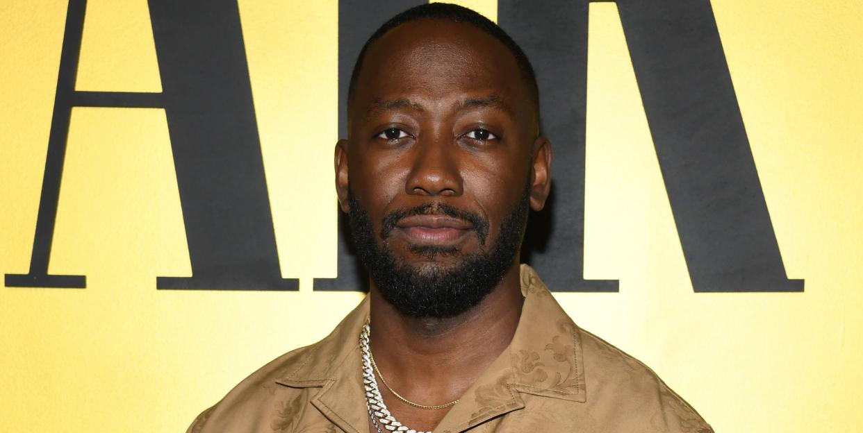 lamorne morris, a man stands with hands in his pockets wearing a brown jumpsuit