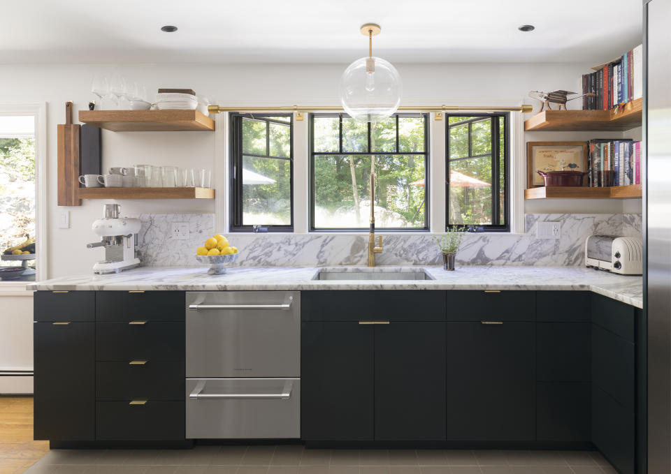 A kitchen with marble countertops, dark cabinetry, and a steel dishwasher