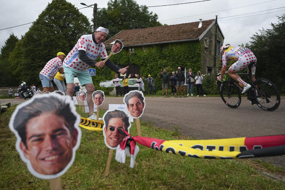 Luc van de Populiere poses for a picture with pictures of Belgium's Wout van Aert as Norway's Jonas Abrahamsen, wearing the best climber's dotted jersey, rear, passes during the eighth stage of the Tour de France cycling race over 183.4 kilometers (114 miles) with start in Semur-en-Auxois and finish in Colombey-les-Deux-Eglises, France, Saturday, July 6, 2024. (AP Photo/Daniel Cole)