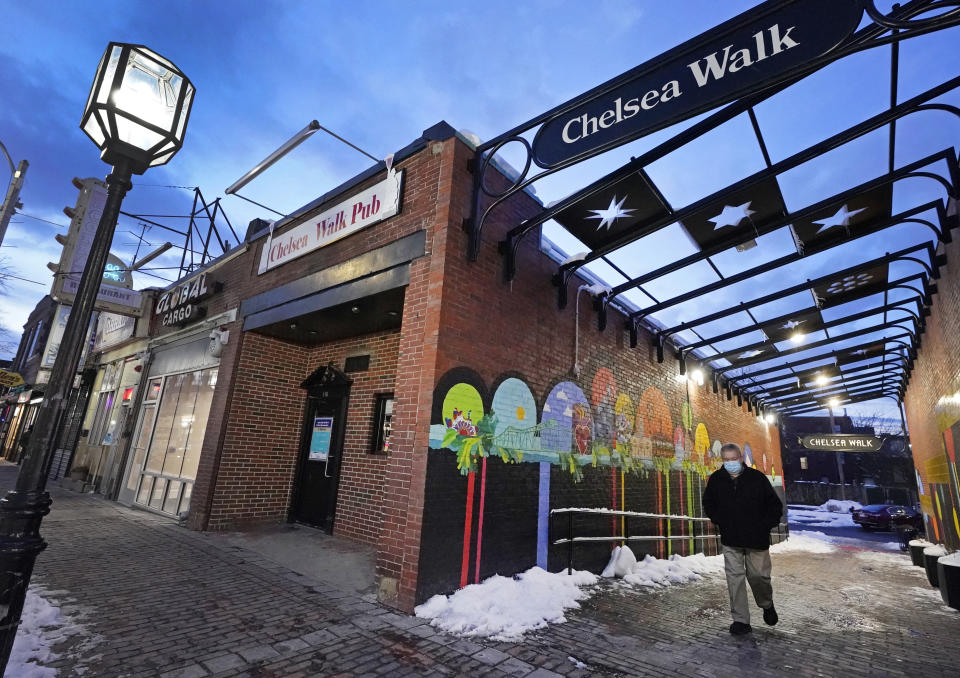 A man walks in downtown Chelsea, Mass., Feb. 10, 2021. Two predominantly Latino cities in neighboring states have had diverging fates in the global rollout of the coronavirus vaccine. Central Falls, R.I., and Chelsea, have been the states’ hardest-hit communities in the pandemic. Public health experts, civil rights groups and immigrant activists have complained for months that Massachusetts isn’t doing nearly enough to ensure that Black and Latino residents are inoculated. (AP Photo/Elise Amendola)