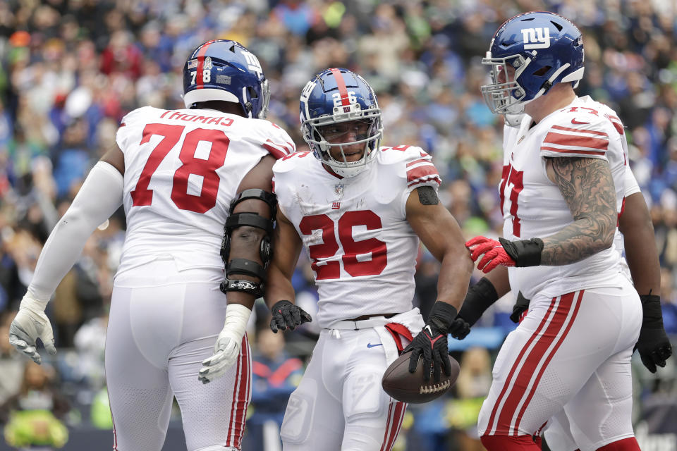 New York Giants running back Saquon Barkley (26) celebrates with offensive tackle Andrew Thomas (78) and guard Jack Anderson after scoring a touchdown against the Seattle Seahawks during the first half of an NFL football game in Seattle, Sunday, Oct. 30, 2022. (AP Photo/John Froschauer)