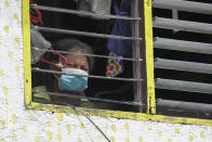 A woman resident wearing a mask looks out from her window as their area is placed under stricter lockdown measures to curb the spread of COVID-19 in Caloocan city, Philippines on Friday, Aug. 14, 2020. The capital and outlying provinces is still under lockdown due to rising COVID-19 cases. (AP Photo/Aaron Favila)