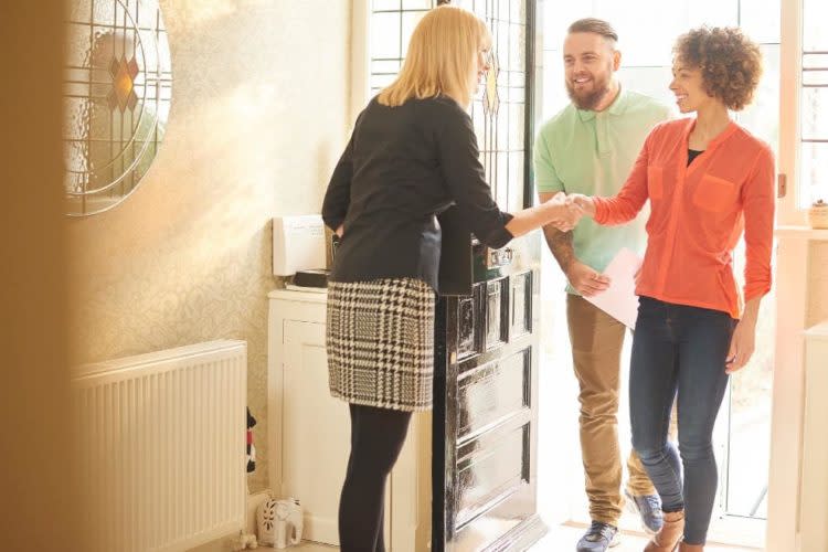 estate agent welcoming a couple to house viewing