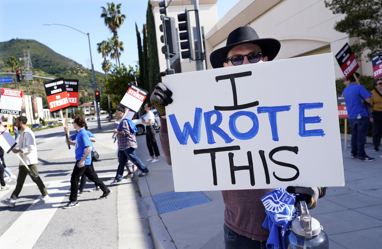Justice Hardy, a writer on the television series "True Lies," holds up a sign as members of The Writers Guild of America picket outside Warner Bros. Studios, Tuesday, May 2, 2023, in Burbank, Calif. The first Hollywood strike in 15 years began Tuesday as the economic pressures of the streaming era prompted unionized TV and film writers to picket for better pay outside major studios, a work stoppage that already is leading most late-night shows to air reruns. (AP Photo/Chris Pizzello)