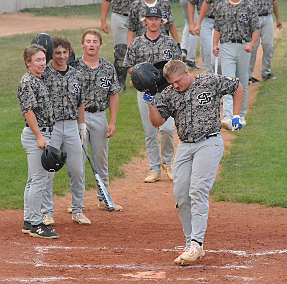 With a group of teammates waiting (from left, Jaiden Smith, Phillip Zens, Zane Backous and Andrew Woehl), Casey Vining of the Aberdeen Smittys steps on home plate after hitting a three-run homer during Game 1 of their best-of-three American Legion Baseball regional playoff series against Watertown Post 17 on Thursday, July 20, 2023 at Watertown Stadium. Aberdeen won 15-4.