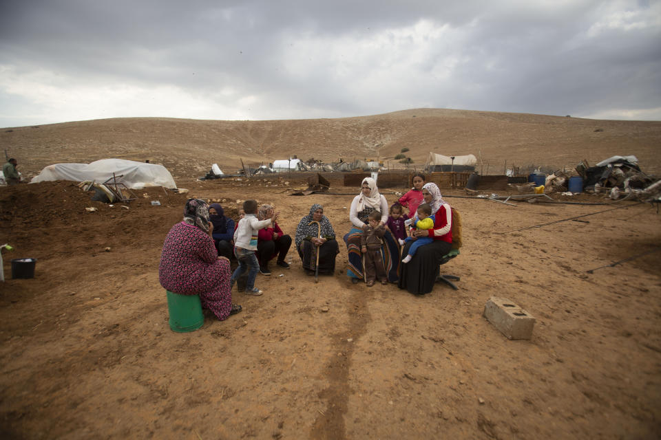 Palestinian women and children in Khirbet Humsu in Jordan Valley in the West Bank, Friday, Nov. 6, 2020. Israeli troops with bulldozers and heavy equipment demolished 18 tents and other structures that housed 74 people, including 41 minors, according to the Israeli rights group B'Tselem. COGAT, the Israeli military body in charge of civilian affairs in the West Bank, said an "enforcement activity" was carried out against seven tents and eight pens that were "illegally constructed" in a firing range. (AP Photo/Majdi Mohammed)