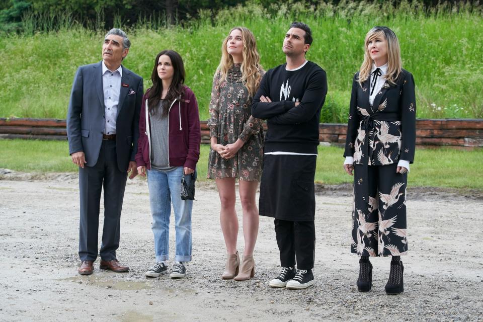 Cast of Schitt's Creek standing together and looking up