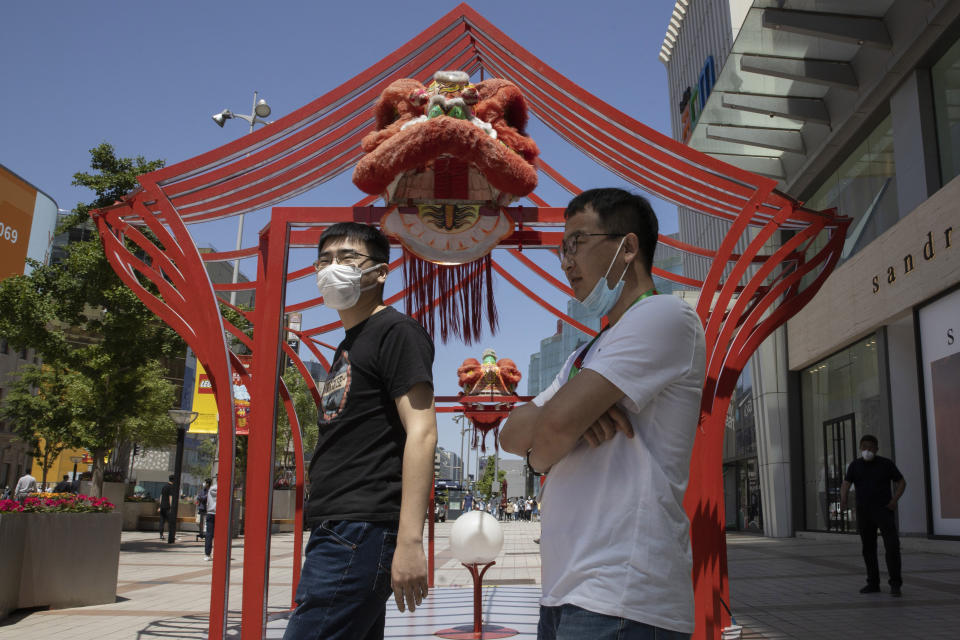Residents wear masks against the coronavirus as they visit a retail district in Beijing on Tuesday, May 12, 2020. Shares were mostly lower Tuesday in Asia as worries over fresh outbreaks of coronavirus cases overshadowed hopes over reopening economies. (AP Photo/Ng Han Guan)