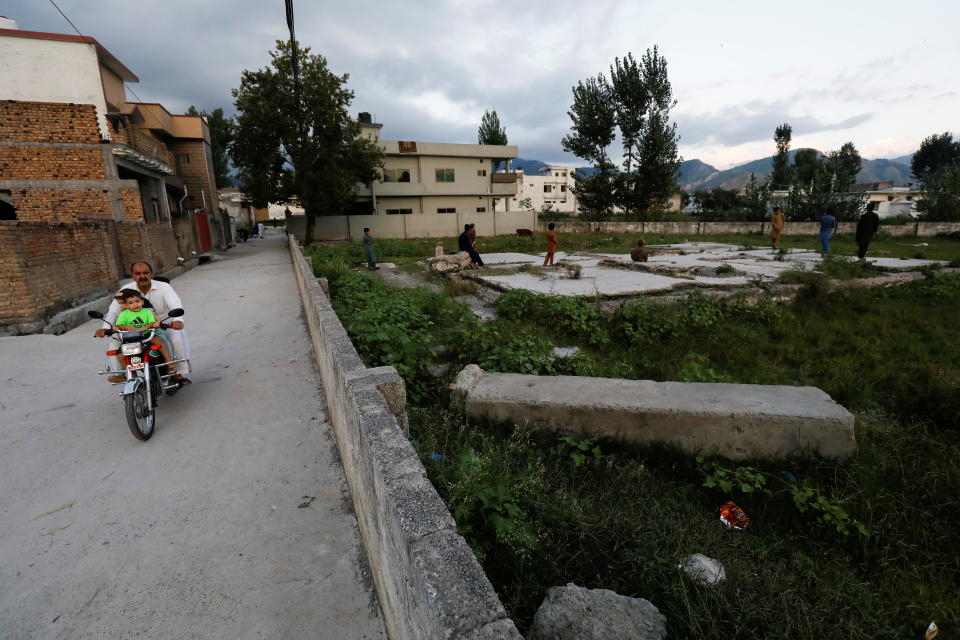 Locals ride past the demolished compound of Osama bin Laden, in Abbottabad, Pakistan, Sept. 11, 2021. 