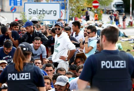 File photo of German police officers standing in front of migrants waiting to cross the border from Austria to Germany near Freilassing, Germany September 17, 2015. REUTERS/Michaela Rehle/Files