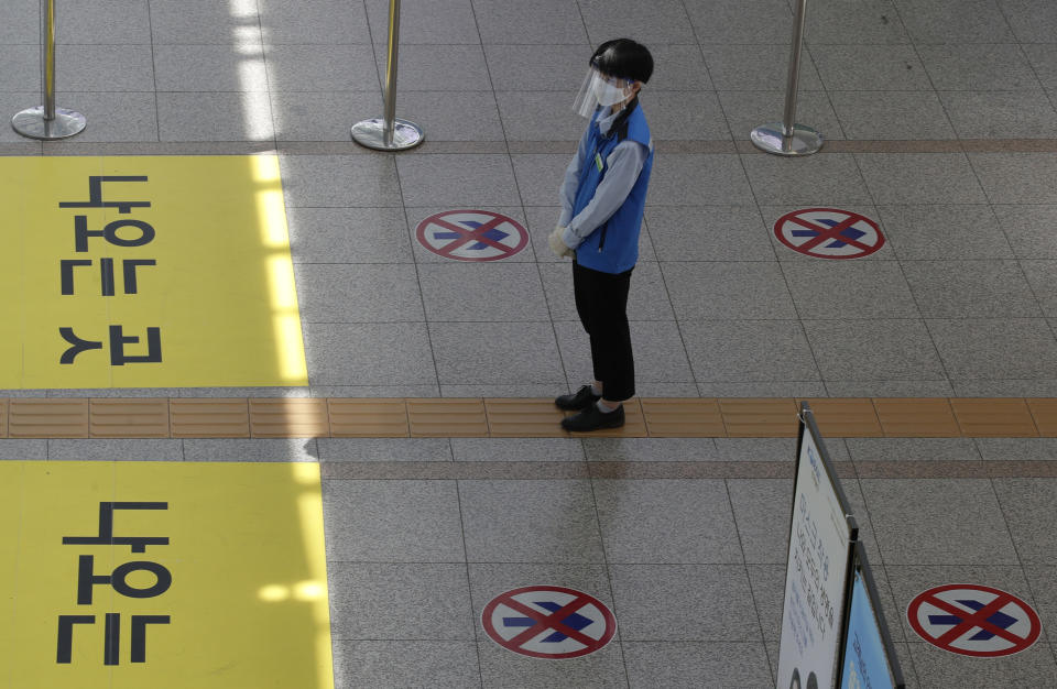 An employee wearing a face mask and face shield stands to guide passengers to maintain a one-way walk flow as a precaution against the coronavirus at the Seoul Railway Station in Seoul, South Korea, Thursday, Sept. 10, 2020. (AP Photo/Lee Jin-man)