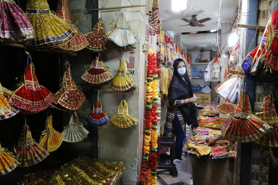 A Hindu woman wearing a mask shops for religious items on the eve of the Hindu festival Navratri in Prayagraj, India, Tuesday, March 24, 2020. Indian Prime Minister Narendra Modi Tuesday announced a total lockdown of the country of 1.3 billion people to contain the new coronavirus outbreak. For most people, the new coronavirus causes only mild or moderate symptoms. For some it can cause more severe illness. (AP Photo/Rajesh Kumar Singh)