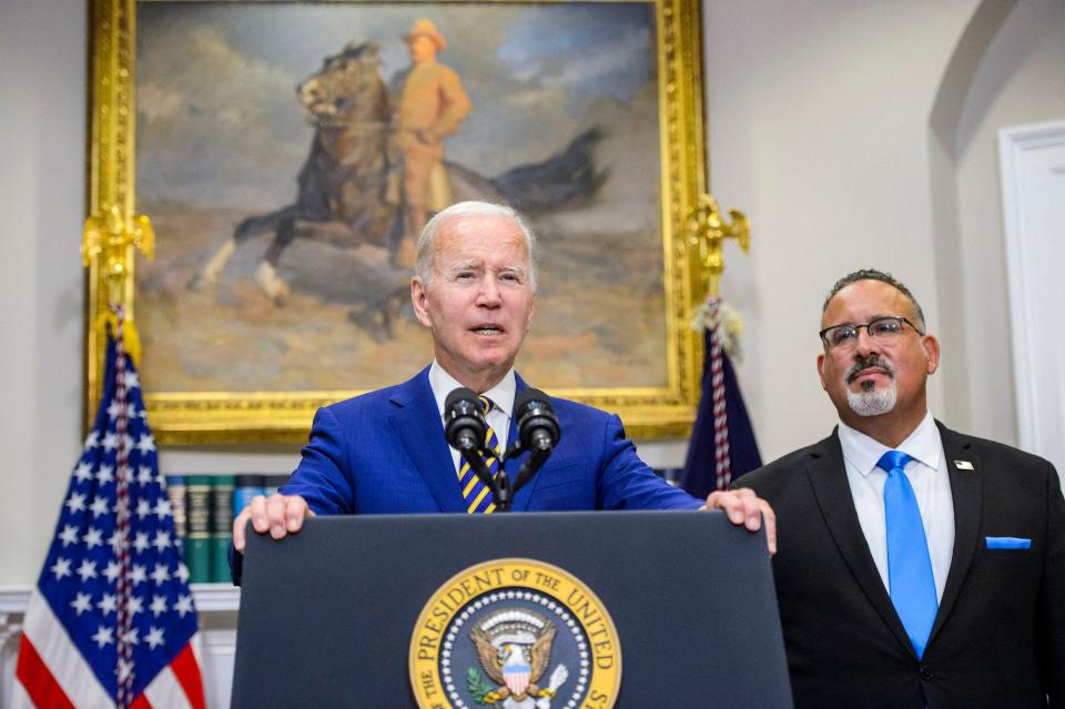 President Joe Biden speaks as Secretary of Education Miguel Cardona looks on after Biden announced a federal student loan relief plan that includes forgiving up to $20,000 for some borrowers and extending the payment freeze.