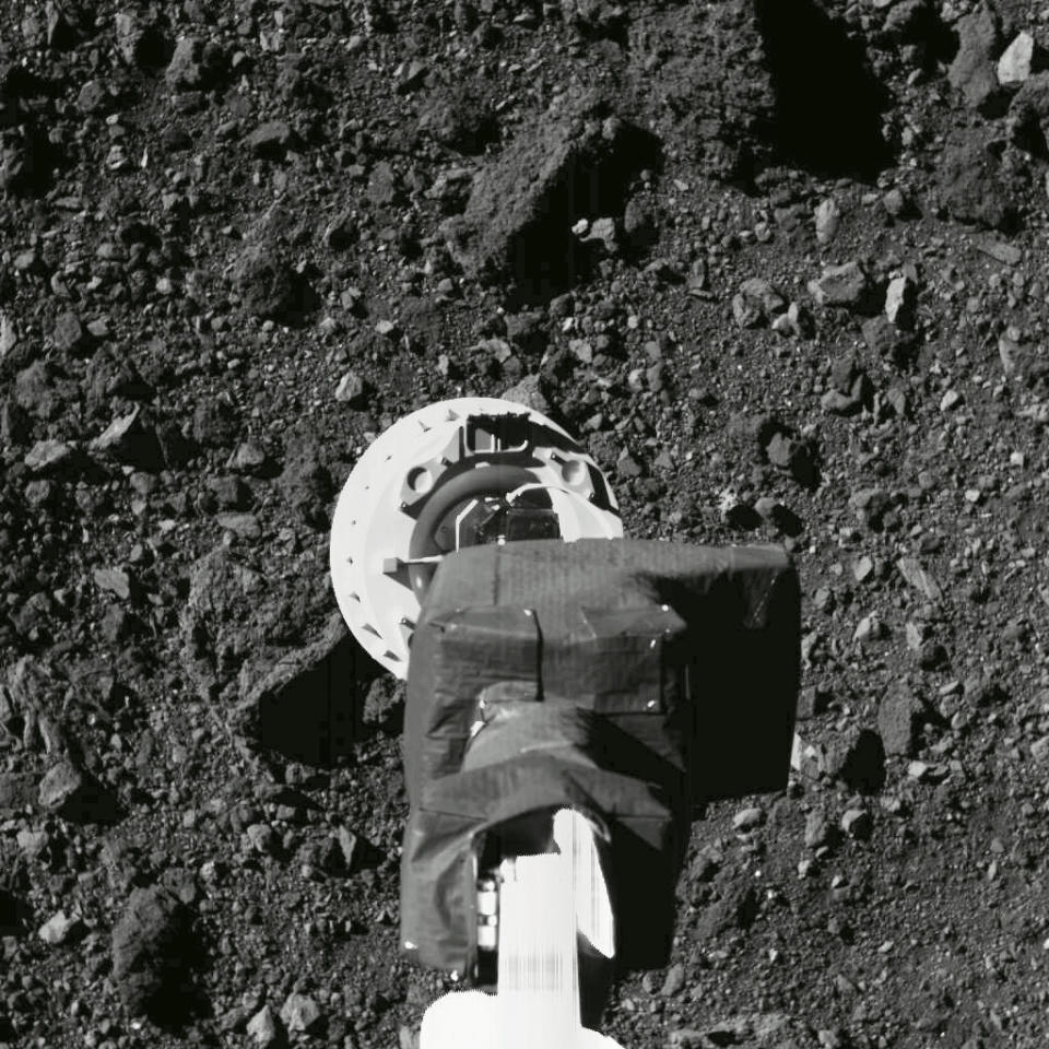 This Aug. 11, 2020 photo shows the sampling arm of the OSIRIS-REx spacecraft during a rehearsal for an approach to the "Nightingale" sample site on the surface of the asteroid Bennu. After almost two years circling the ancient asteroid, OSIRIS-REx will attempt to descend to the treacherous, boulder-packed surface and snatch a handful of rubble on Tuesday, Oct. 20, 2020. (NASA/Goddard/University of Arizona via AP)