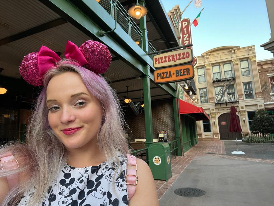 jenna posing for a selfie in front of pizza rizzo at hollywood studios in disney world