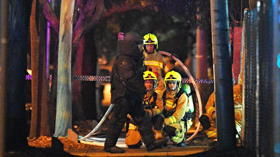 NSW Emergency services personnel are seen crouching down near the police station after the attack. Photo: AAP