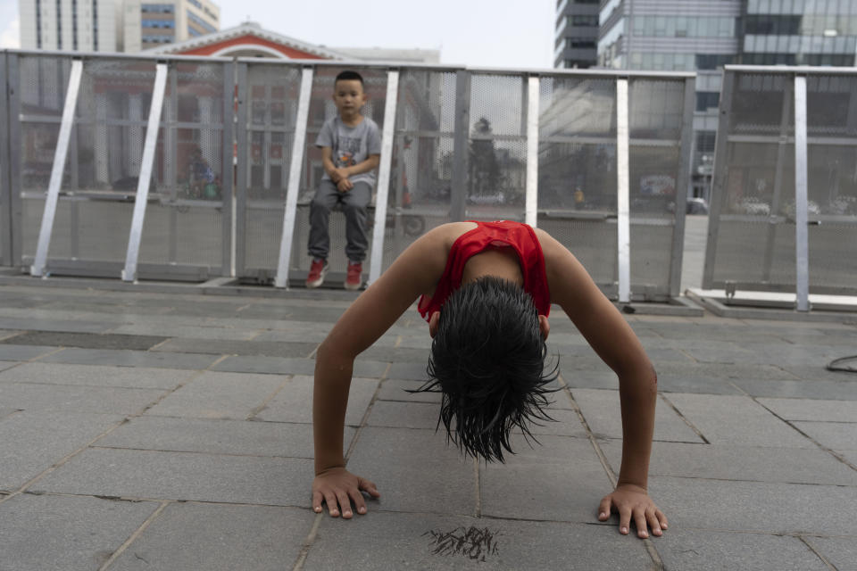 Twelve-year-old Gerelt-Od Kherlen does pushups to stretch after defeating his opponent to win a bronze medal boxing match on Sukhbaatar Square in Ulaanbaatar, Mongolia, Tuesday, July 2, 2024. Growing up in a Ger district without proper running water, Gerelt-Od fetched water from a nearby kiosk every day for his family. Carrying water and playing ball with his siblings and other children made him strong and resilient. (AP Photo/Ng Han Guan)