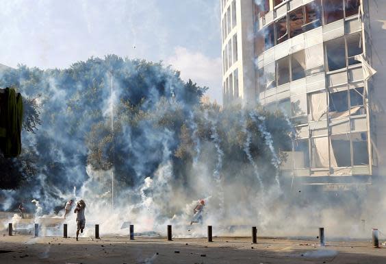 Demonstrators run to take cover from tear gas fired by police during a protest (REUTERS)