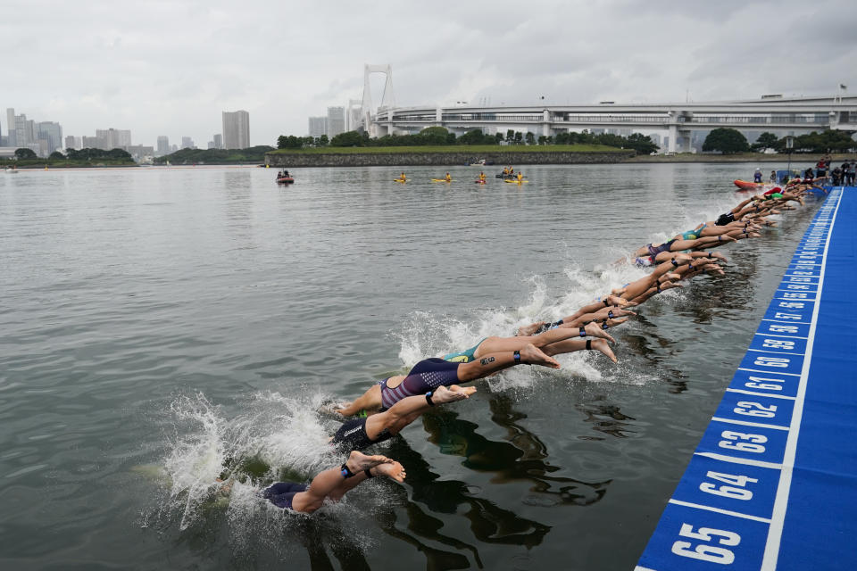 FILE - In this Aug. 15, 2019, file photo, athletes dive into the water at the start line during a women's triathlon test event at Odaiba Marine Park, a venue for marathon swimming and triathlon at the Tokyo 2020 Olympics, in Tokyo. The IOC moved next year’s Tokyo Olympic marathons and race walks out of the Japanese capital to avoid the stifling heat and humidity. Some swimmers and an 11,000-member coaching body want similar treatment: find an alternative to the distance-swimming venue in Tokyo Bay known as the “Odaiba Marine Park.”(AP Photo/Jae C. Hong, File)