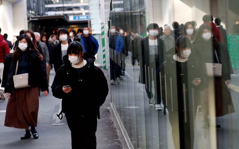 Pedestrians wearing surgical masks make their way in front of Yokohama station in Yokohama