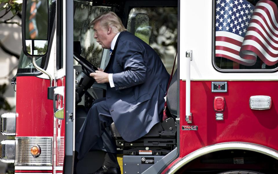 U.S. President Donald Trump sits in a fire truck while participating in a Made in America event - Credit: Bloomberg