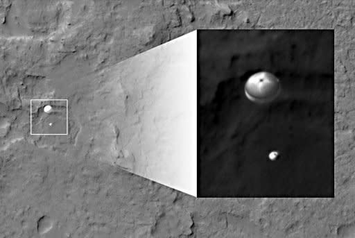 Image provided by NASA on August 6 shows the Curiosity rover and its parachute -- from the perspective of the Mars Reconnaissance Orbiter -- descending towards the surface of Mars. The rover is descending towards the etched plains just north of the sand dunes that fringe "Mt. Sharp"